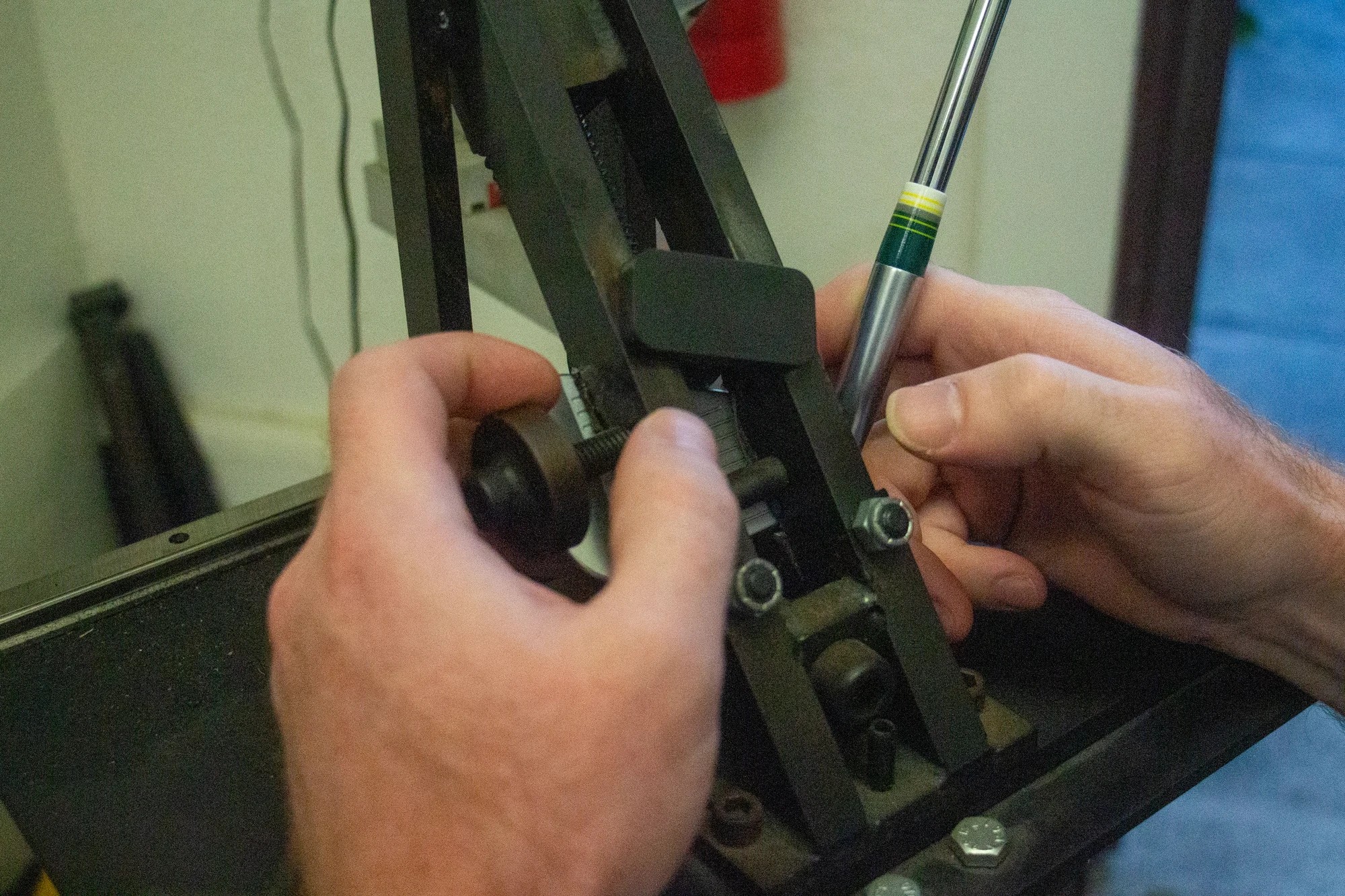 Hands measuring a golf club at the Alameda Golfworks workbench